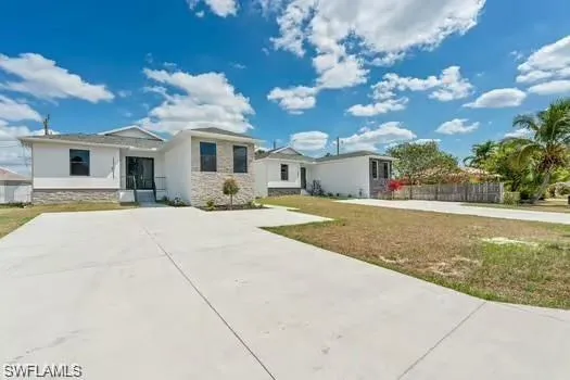 View of front of home featuring stone siding, stucco siding, driveway, and a front yard