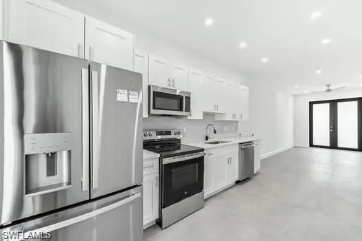 Kitchen #1 featuring appliances with stainless steel finishes, white cabinetry, light countertops, french doors, and recessed lighting