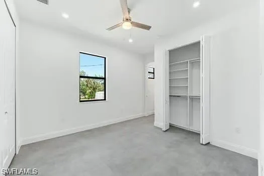 Primary Bedroom on main entrance sidewith concrete floors, recessed lighting, ceiling fan, and a custom closet