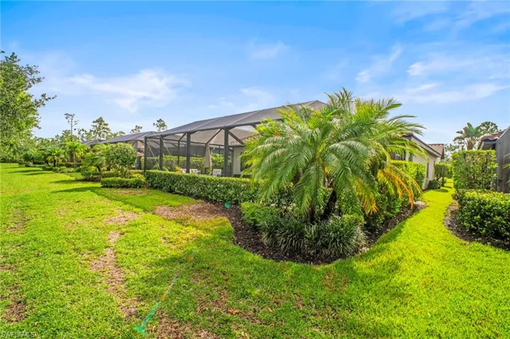 View of grassy yard featuring a lanai and a sunroom