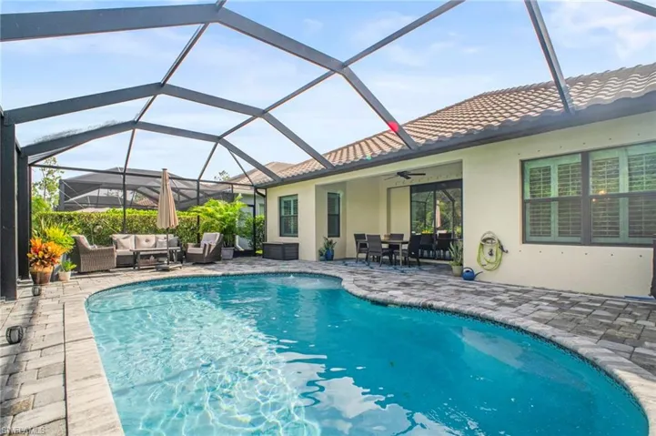 Swimming pool featuring a sunroom, an outdoor living / dining area, a patio, and a lanai
