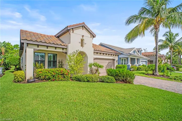Mediterranean / spanish-style house with a tiled roof, stucco siding, a front lawn, a garage, and decorative driveway
