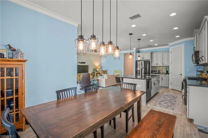 Dining space featuring light wood-style floors, crown molding, and recessed lighting