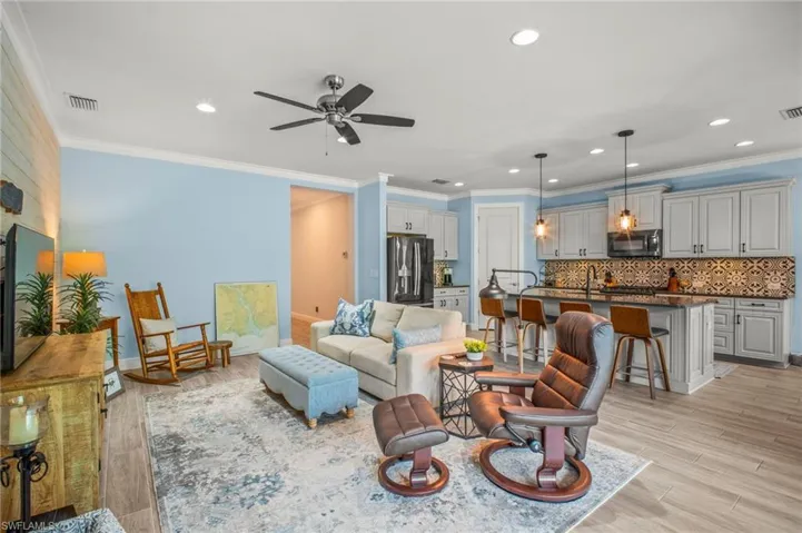 Living area featuring ornamental molding, a ceiling fan, light wood-style flooring, and recessed lighting