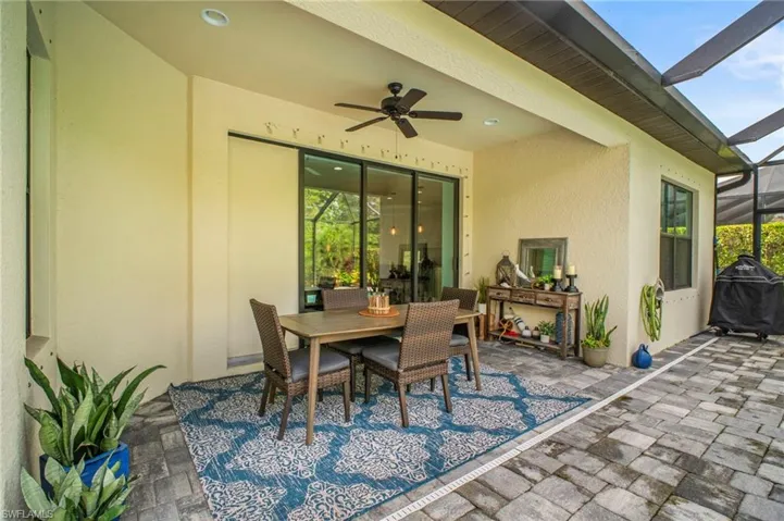 View of patio with glass enclosure, a grill, outdoor dining space, and ceiling fan