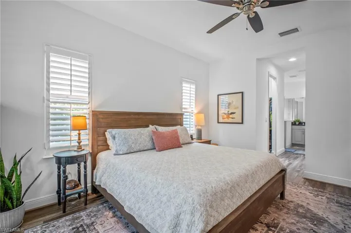 Bedroom featuring dark wood finished floors, a ceiling fan, and ensuite bathroom