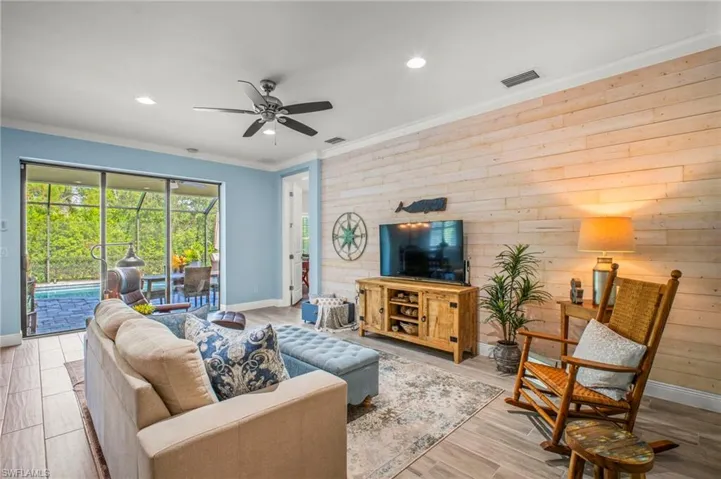 Living room featuring wood walls, ceiling fan, light wood-type flooring, crown molding, and recessed lighting