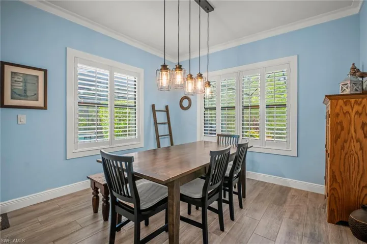 Dining space featuring wood finished floors and crown molding