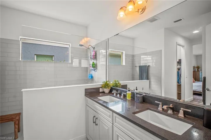 Bathroom featuring ensuite bath, double vanity, and a walk in shower