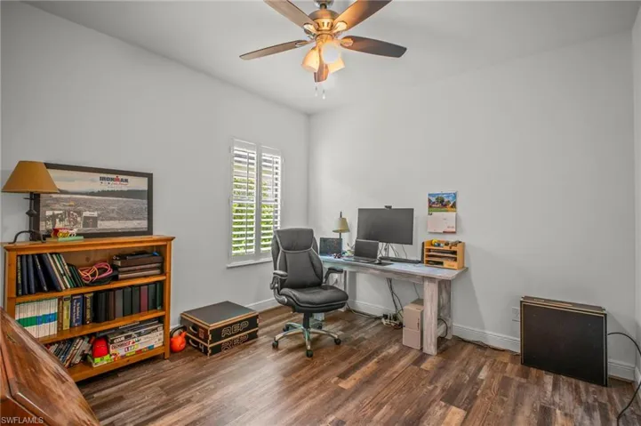 Home office with dark wood finished floors and ceiling fan