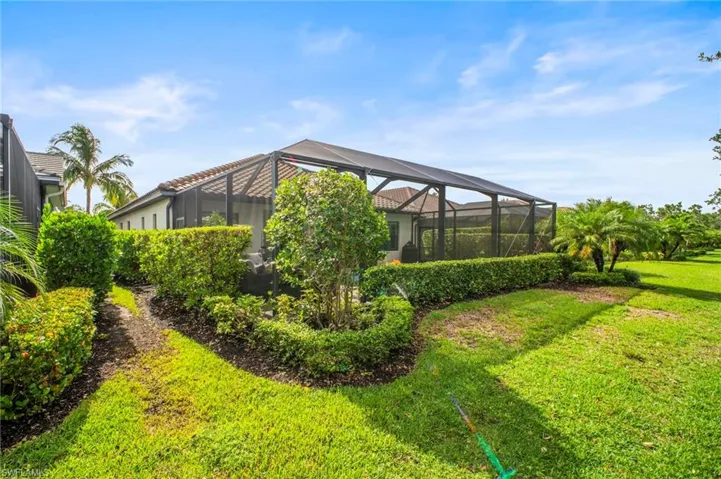 View of green lawn featuring a sunroom and glass enclosure