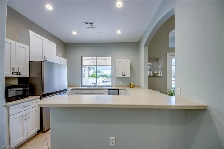 Kitchen featuring white cabinetry, light-toned countertops, recessed lighting, and a stainless steel refrigerator