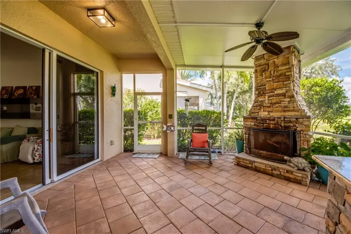 Screened patio featuring a stone-clad fireplace, ceiling fan, and sliding glass doors