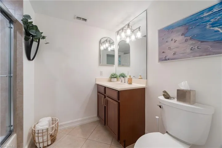 Bathroom with walk in shower, vanity, toilet, and tile patterned floors