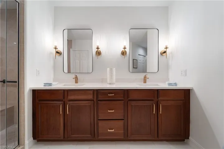 Bathroom featuring tile patterned flooring, a shower with shower door, and vanity