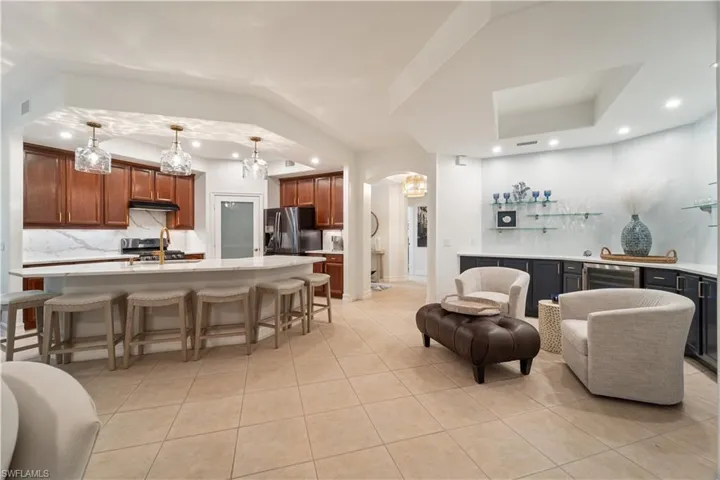 Living room featuring a tray ceiling, an inviting chandelier, and light tile patterned floors