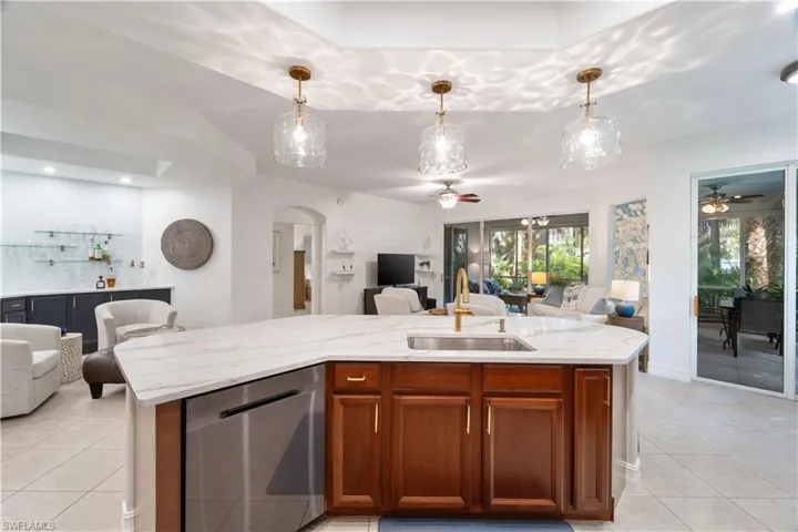 Kitchen featuring hanging light fixtures, an island with sink, light tile patterned floors, ceiling fan, and sink