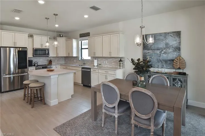 Kitchen featuring appliances with stainless steel finishes, a breakfast bar, decorative backsplash, pendant lighting, and recessed lighting