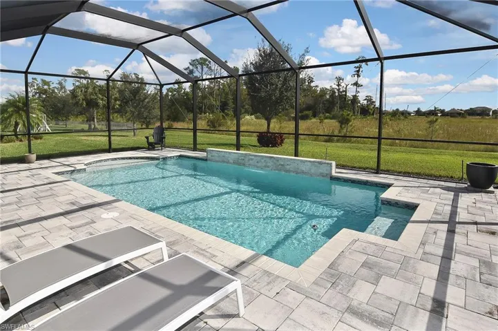 Swimming pool featuring a lawn, glass enclosure, a patio area, and a sunroom