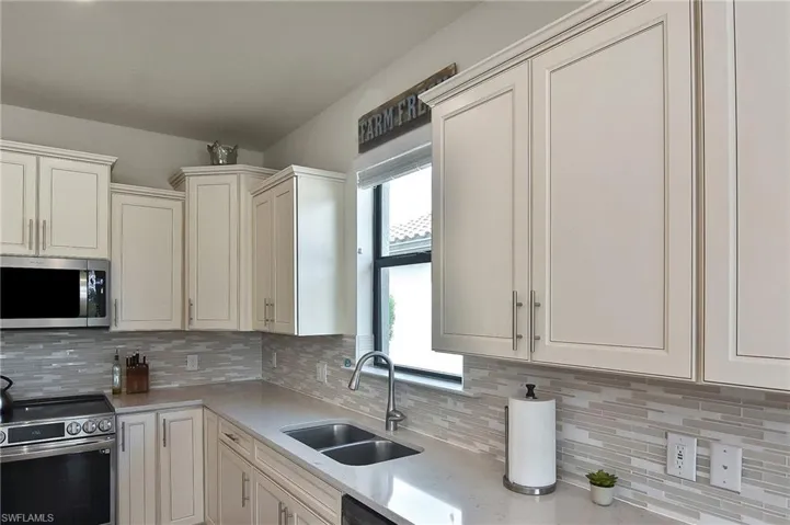 Kitchen with stainless steel appliances, backsplash, and light stone counters