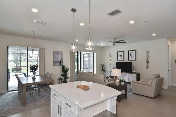Kitchen featuring a kitchen island, light stone counters, white cabinetry, open floor plan, and recessed lighting