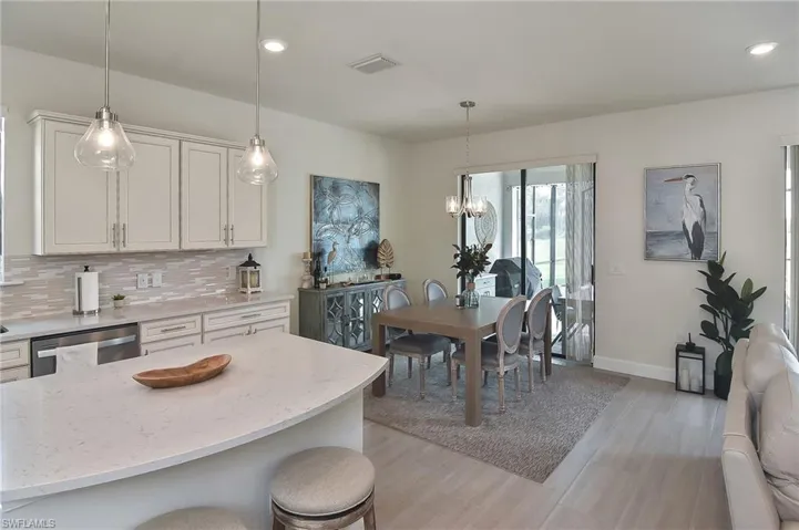Kitchen with light stone counters, recessed lighting, hanging light fixtures, a kitchen breakfast bar, and tasteful backsplash