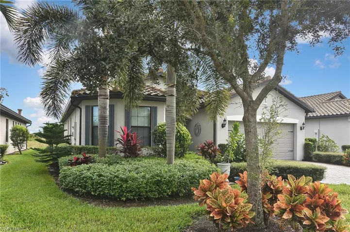 View of front of home with a garage, stucco siding, a front yard, and driveway