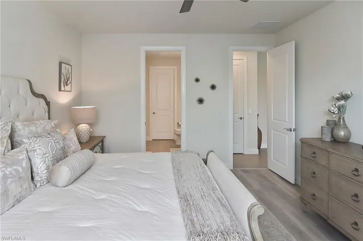 Bedroom featuring ensuite bath, light wood-style flooring, and a ceiling fan