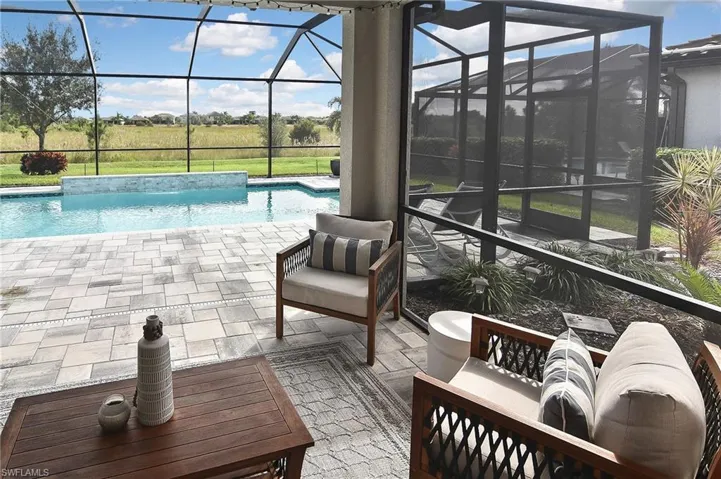 Outdoor pool featuring glass enclosure, a patio, a sunroom, and an outdoor hangout area
