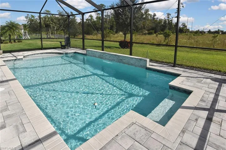 Swimming pool featuring a lawn, a lanai, a patio area, and a sunroom