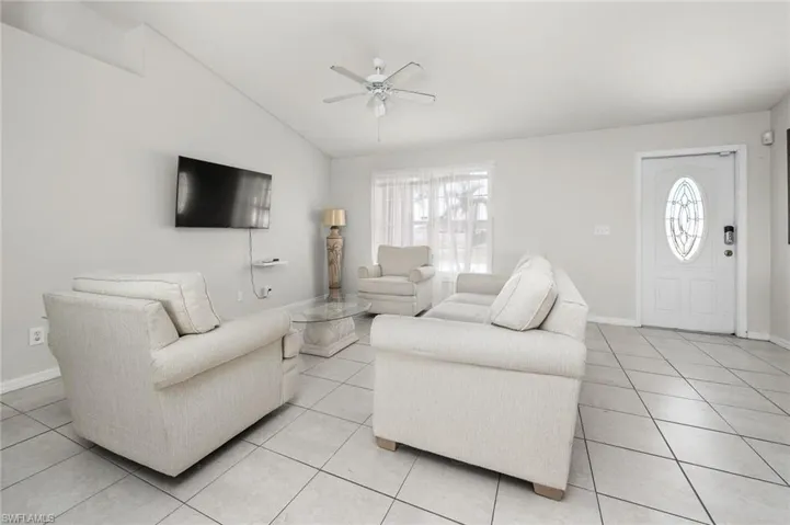 Tiled living room with vaulted ceiling, a wealth of natural light, and ceiling fan