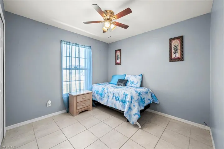 Tiled bedroom featuring ceiling fan