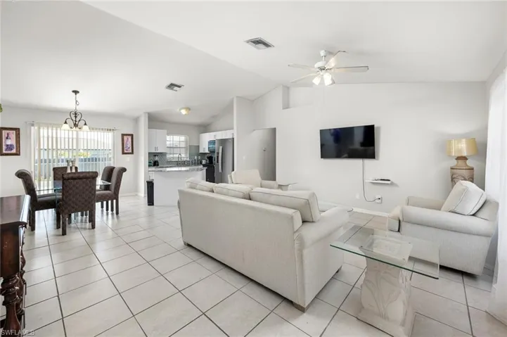 Living room with tile floors, ceiling fan, and a lofted ceiling