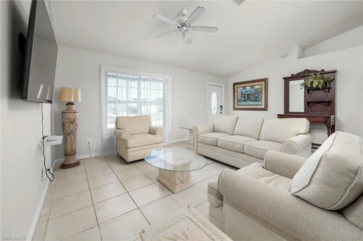 Tiled living room featuring ceiling fan and lofted ceiling