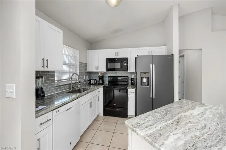 Kitchen featuring white cabinets, sink, lofted ceiling, and appliances