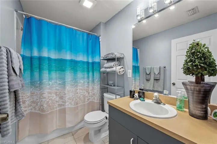 Full bathroom with tile floors, shower / bathtub combination with curtain, vanity, and toilet
