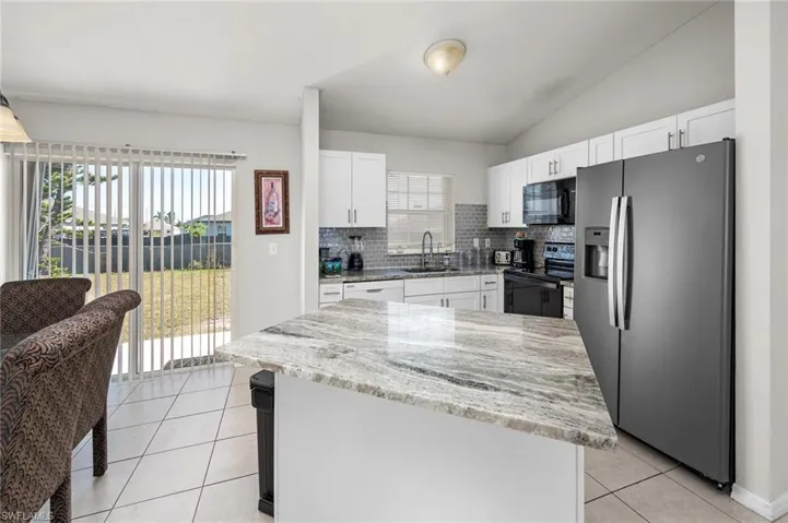 Kitchen featuring a wealth of natural light, white cabinetry, sink, and appliances