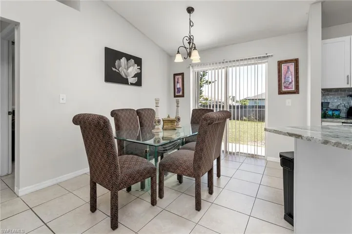 Tiled dining room with a chandelier and vaulted ceiling