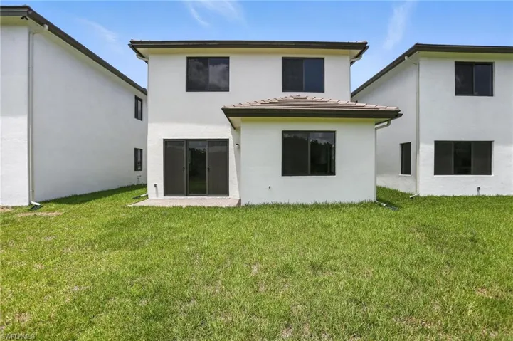 Back of house featuring stucco siding and a yard