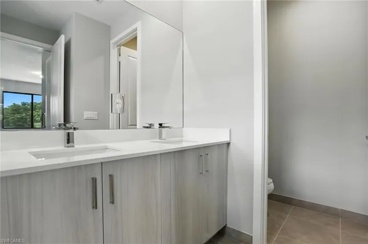 Bathroom with double vanity and light tile patterned floors