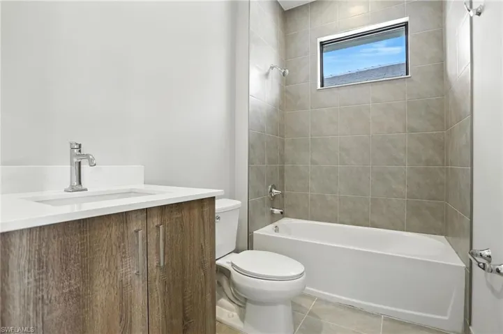 Full bathroom with vanity, washtub / shower combination, and light tile patterned floors