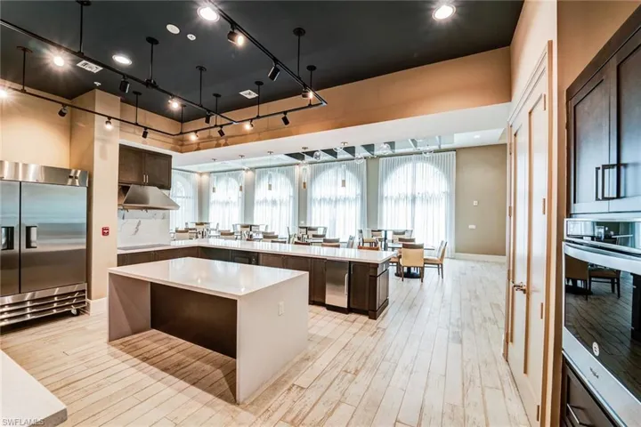 Kitchen featuring stainless steel appliances, a peninsula, light stone counters, light wood-style flooring, and dark brown cabinetry
