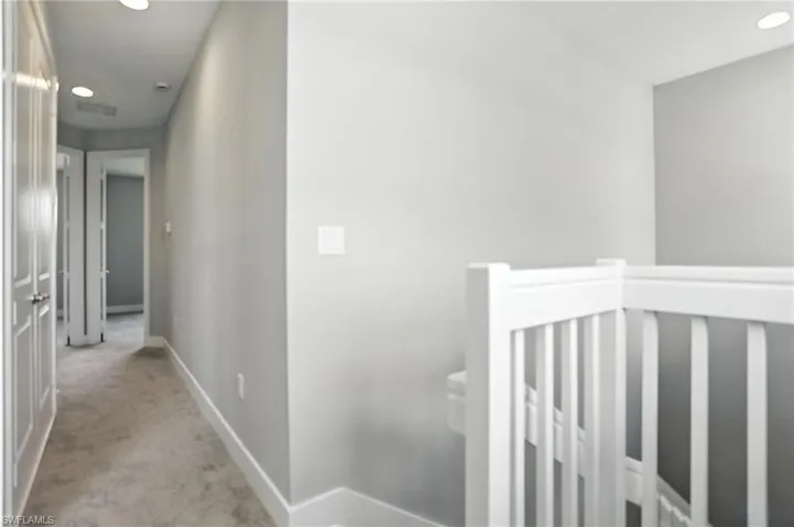 Hallway with recessed lighting, an upstairs landing, and light carpet