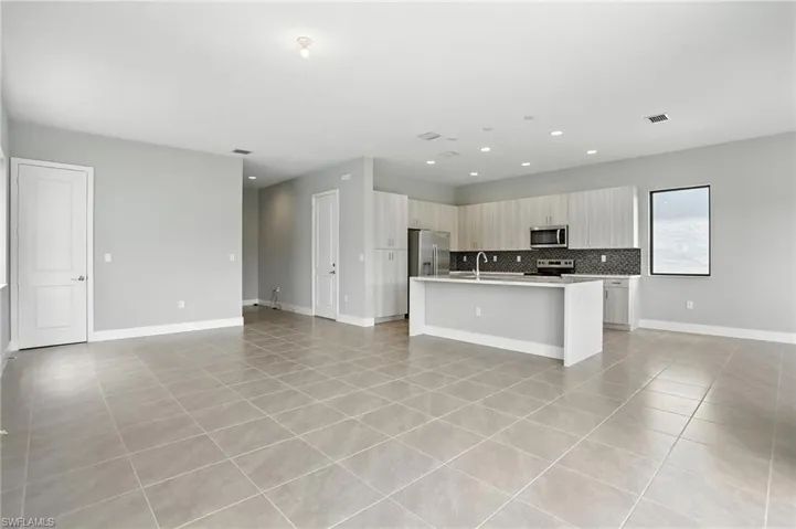 Kitchen featuring light tile patterned floors, a center island with sink, open floor plan, stainless steel appliances, and recessed lighting
