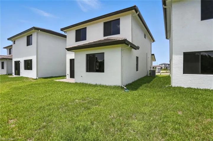Rear view of property with stucco siding and a yard