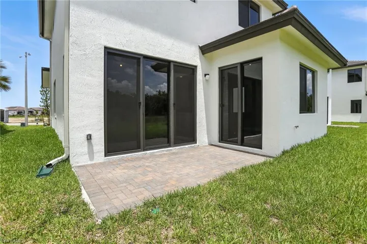 Rear view of property with a lawn, a patio, and stucco siding