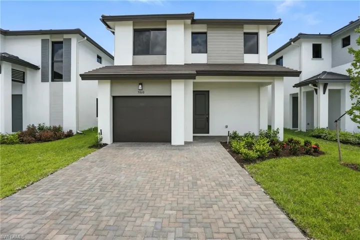 Contemporary home featuring a front lawn, stucco siding, decorative driveway, and an attached garage