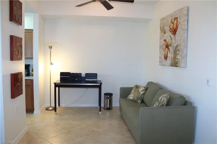 Open Den featuring light tile patterned floors and a ceiling fan