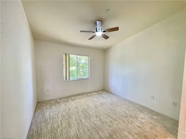 Carpeted bedroom with a new ceiling fan and walk in closet