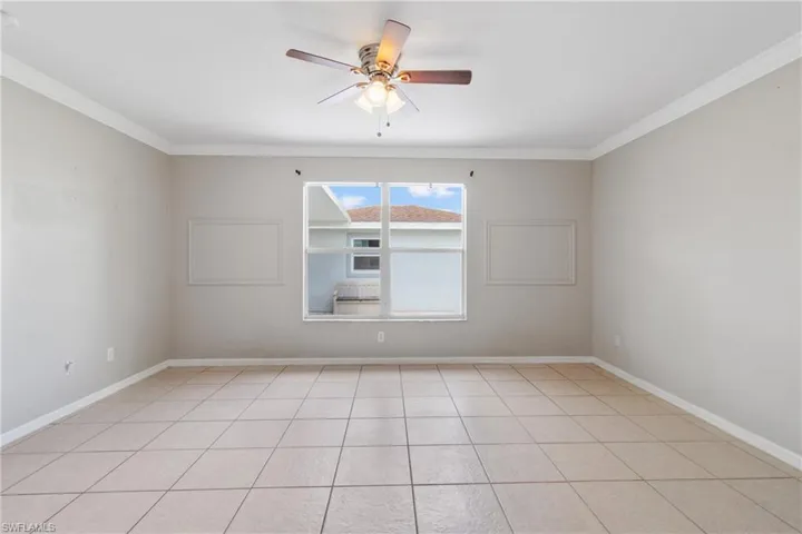 Spare room featuring a ceiling fan, crown molding, and light tile patterned floors
